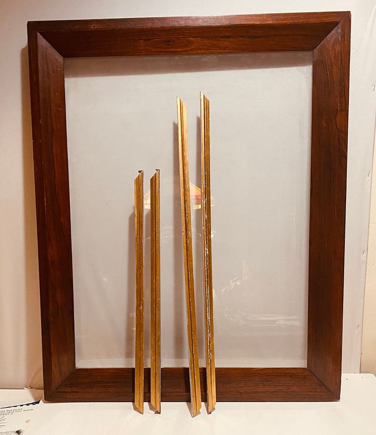 three wooden sticks are placed in front of a frame