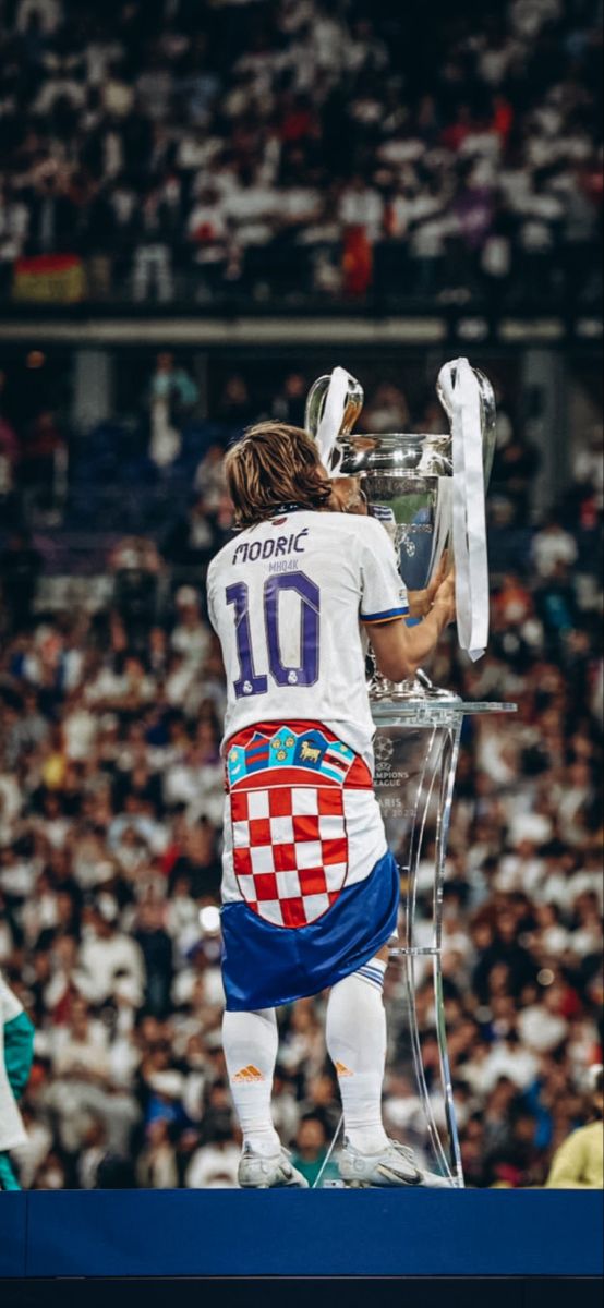 a man standing on top of a trophy in front of a crowd