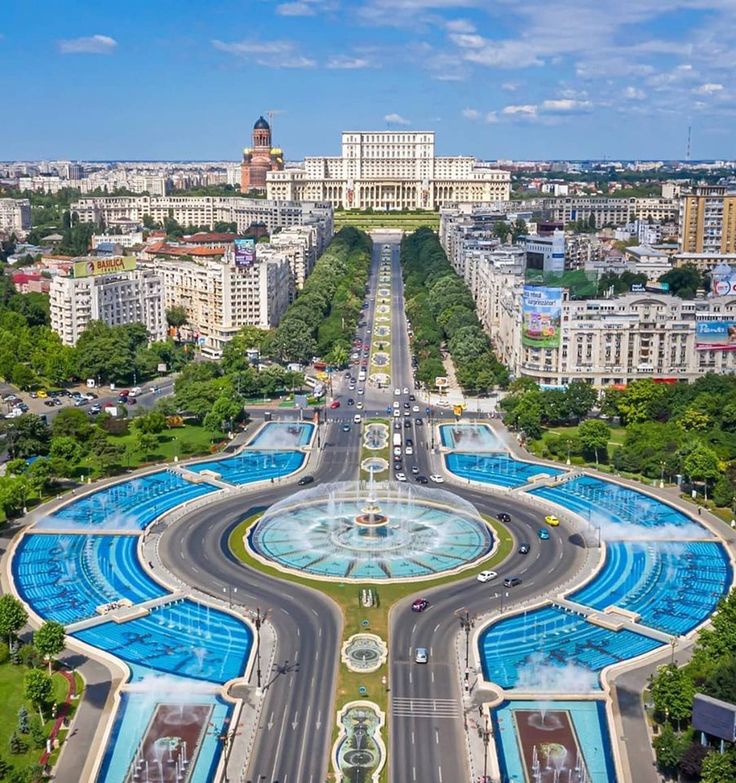 an aerial view of a city with fountains in the center and buildings around it on both sides