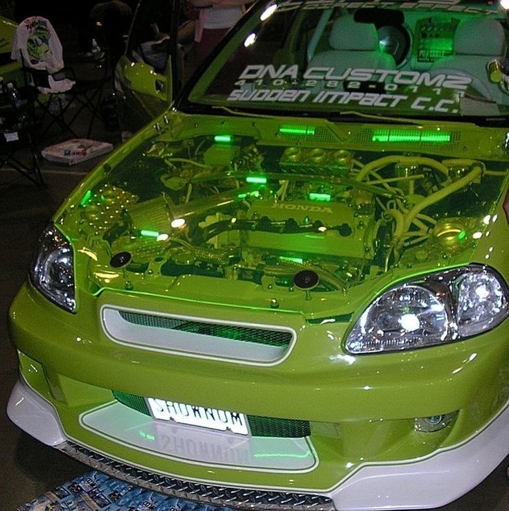 a green car parked in a garage with its hood up and the engine on it's side