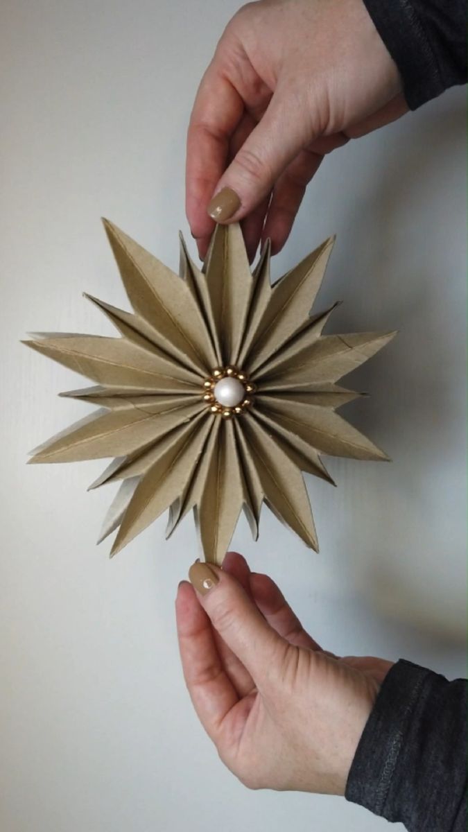 two hands holding an origami star decoration