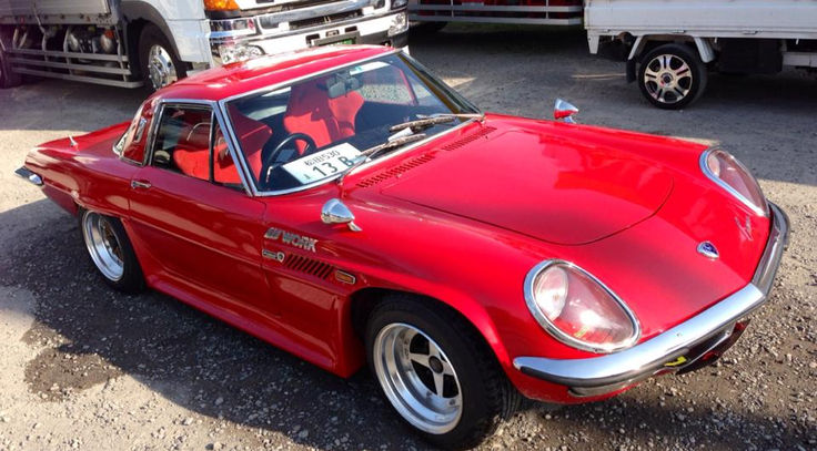 a red sports car parked next to a white truck