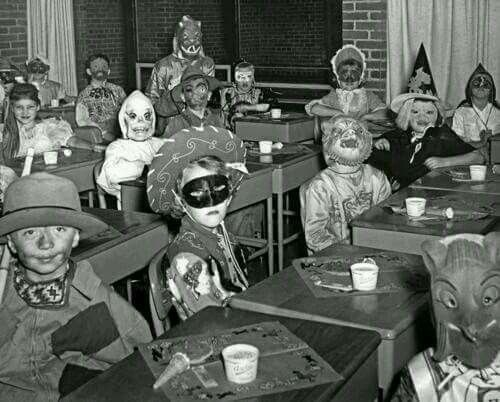 an old black and white photo of children in costumes at desks with masks on their faces