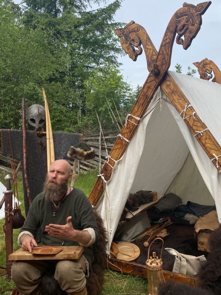 a man sitting in front of a teepee tent