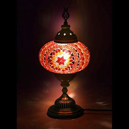 a lamp that is on top of a wooden stand with a red and yellow light