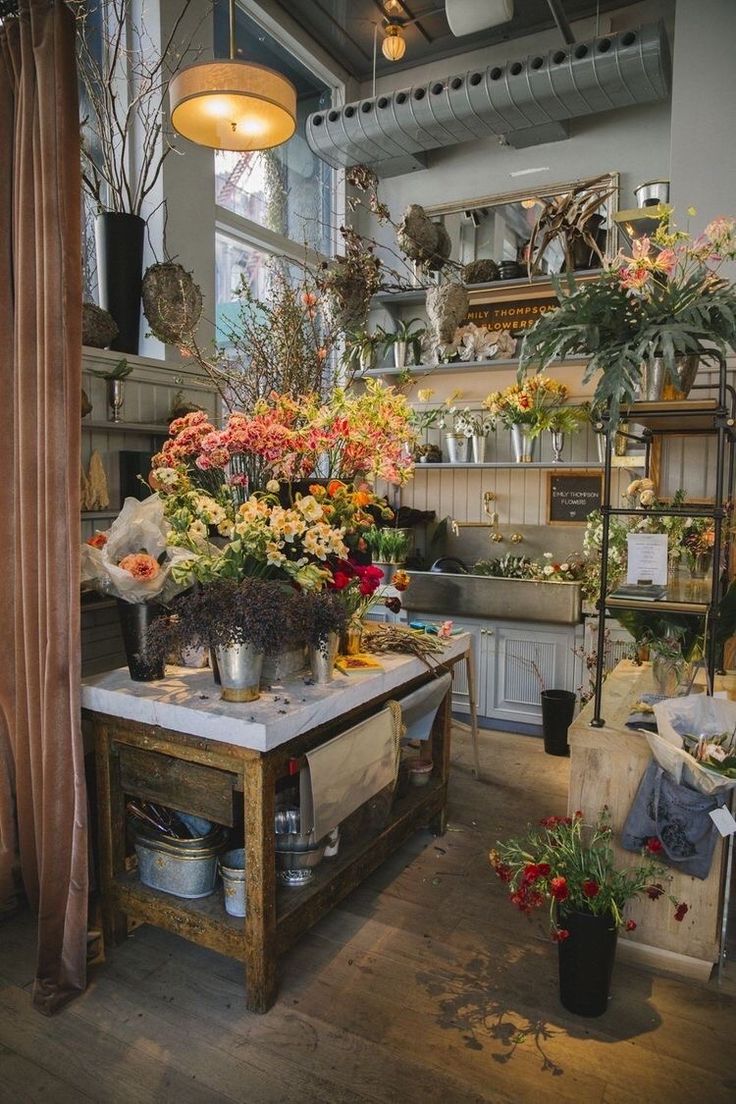 a room filled with lots of different types of flowers and plants in pots on top of a table