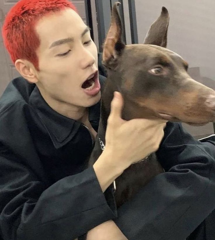 a man with red hair is holding a dog