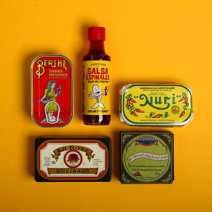 four different tins are arranged on a yellow surface, one has an empty bottle and the other contains various condiments