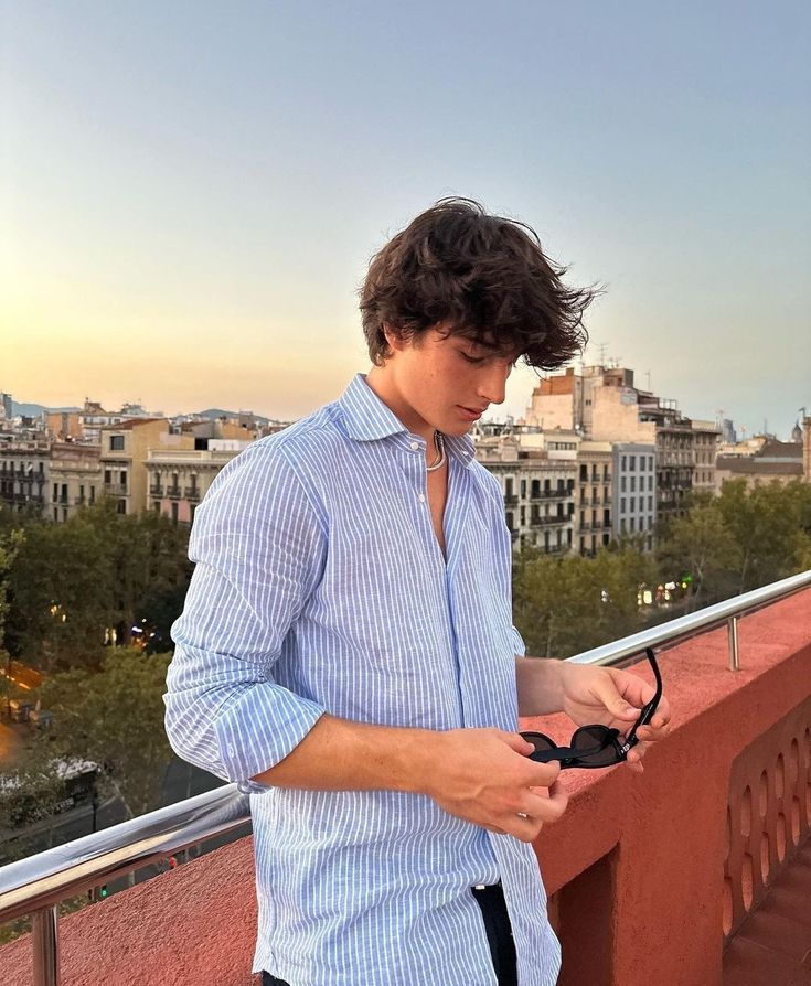 a man standing on top of a balcony holding a pair of black scissors in his hand