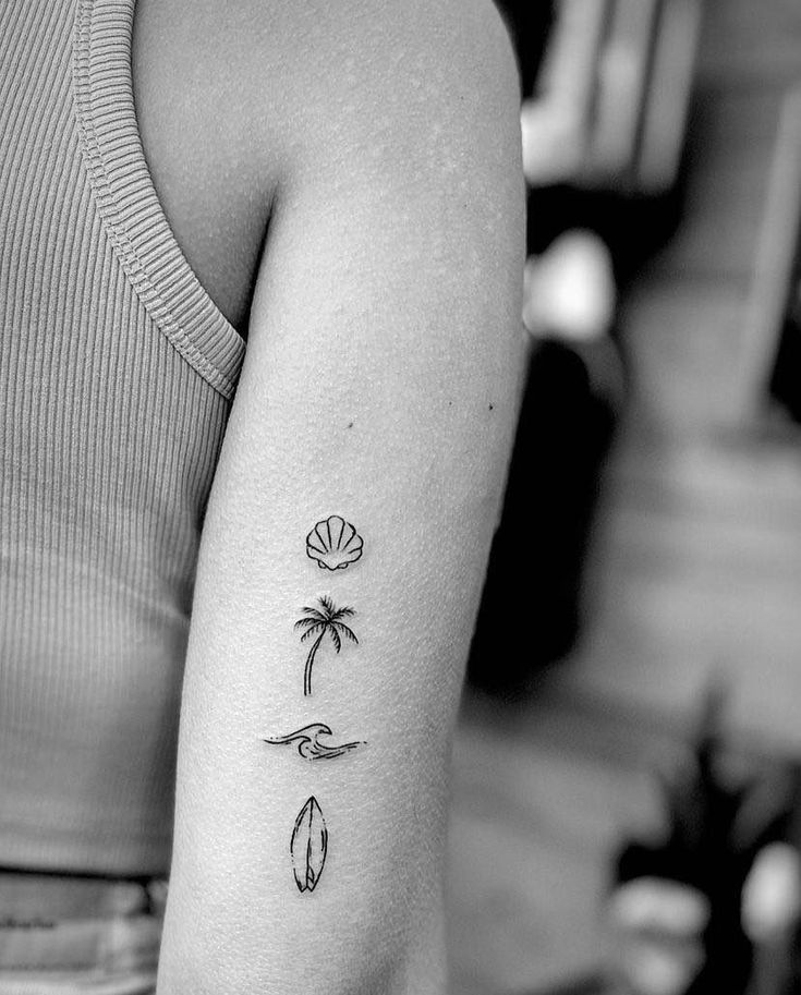 a black and white photo of a woman's arm with three tattoos on it