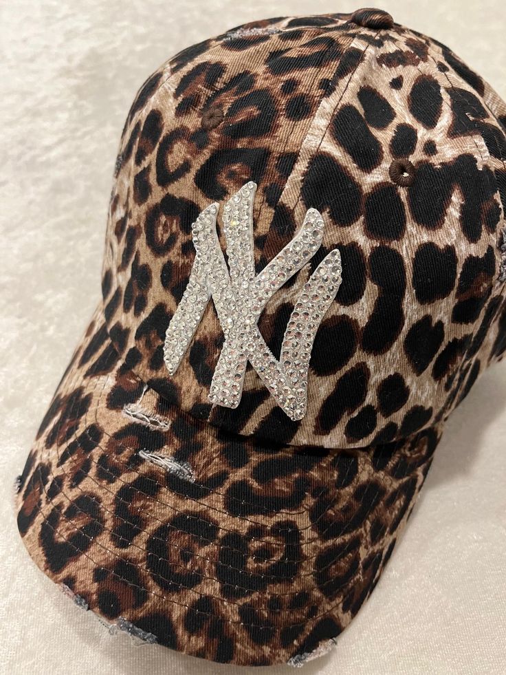 NEW YORK LEOPARD DISTRESSED BLING HAT HAND EMBELLISHED WITH 200+ SWAROVSKI CRYSTALS PRECISE CRYSTAL PLACEMENT ATTENTION TO DETAIL.  THIS HAT DOESN'T LACK BRILLIANCE. ADJUSTABLE BACK STRAP PLEASE FAVORITE MY ETSY SHOP SO YOUR FIRST TO SEE ALL MY CUSTOM HATS https://allabouttheblingcc.etsy.com Winter Hats Outfit, Cheetah Print Accessories, Fitted Cap Outfit Black Women, Cheetah Print Hat Outfit, Bedazzled Fitted Hat, Rhinestone Clothes, Brown Rhinestone Hat, Leopard Ny Hat, Crystal Placement