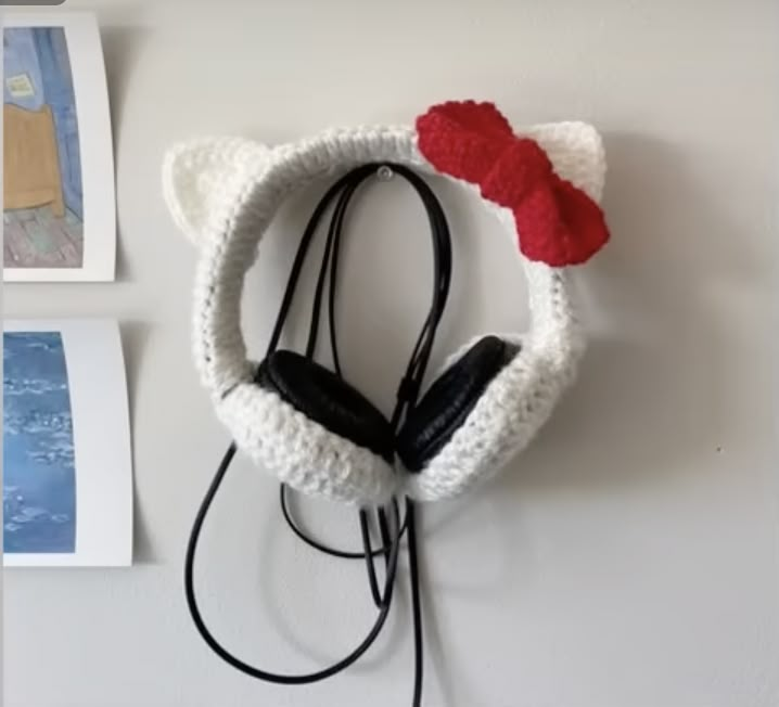 there is a crocheted cat head with earphones attached to the wall next to pictures