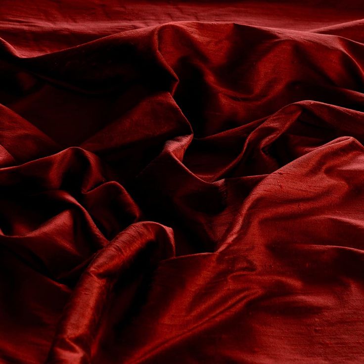 a red blanket is laying on top of a bed with it's sheets folded down