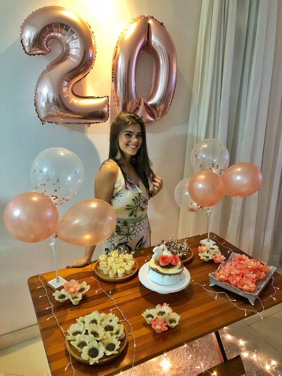 a woman standing in front of a table with desserts and balloons