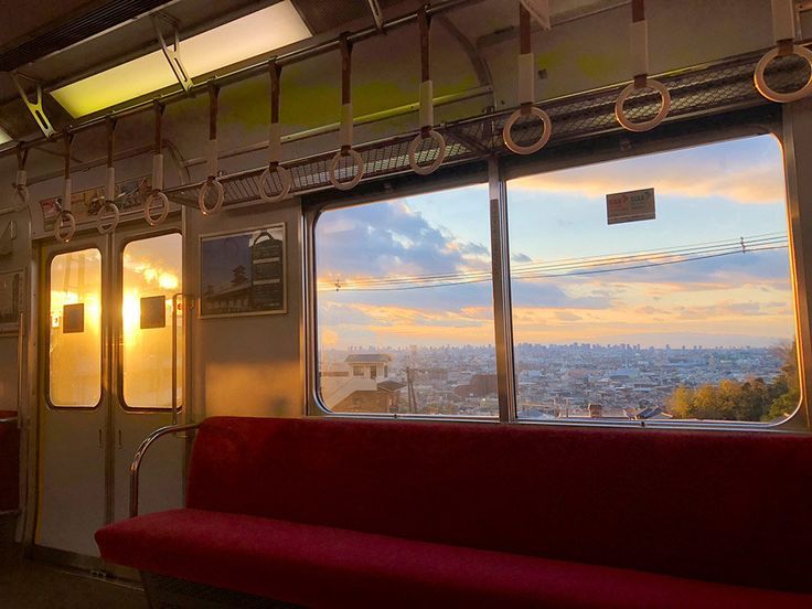 the inside of a train car with two windows looking out at cityscape in the distance