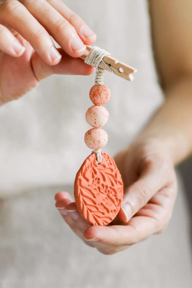 a woman is holding an orange heart shaped beaded keychain in her hands