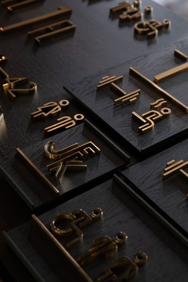 several different types of metal letters and numbers on black wood with gold trimmings