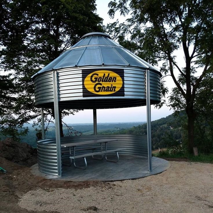 a large metal structure with a yellow sign on it's side and trees in the background