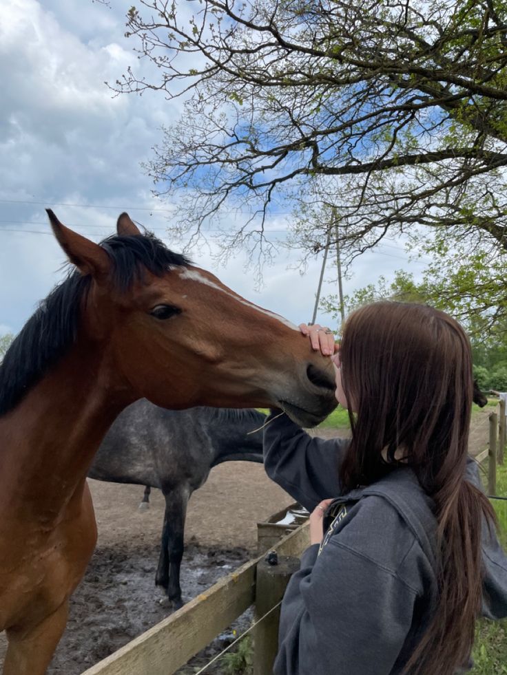 a woman standing next to a brown horse