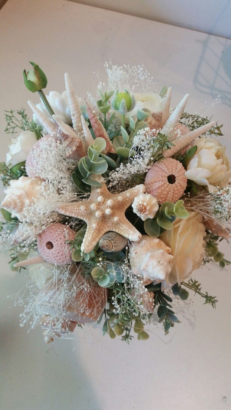 a starfish bouquet on a table with flowers and seashells in the center