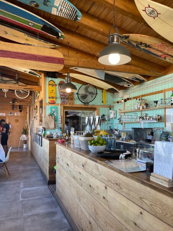 the inside of a restaurant with surfboards hanging from the ceiling