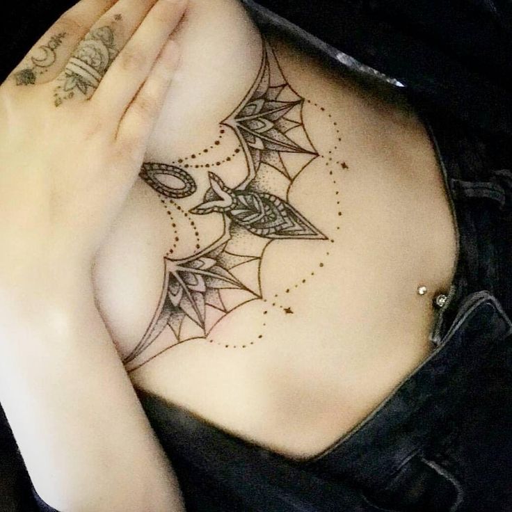 a woman with tattoos on her chest is holding her hand up to her chest and looking at the camera