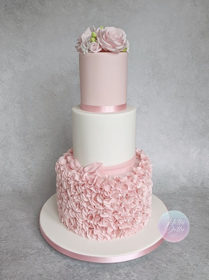 a three tiered cake with pink flowers on top and white frosting around the edges