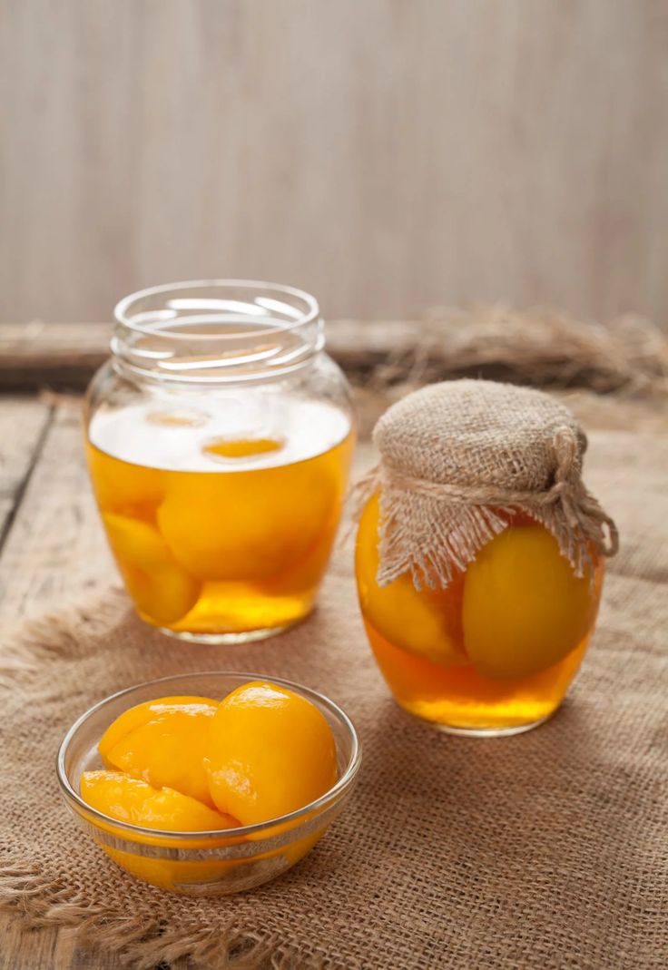 two jars filled with oranges sitting on top of a burlied tablecloth