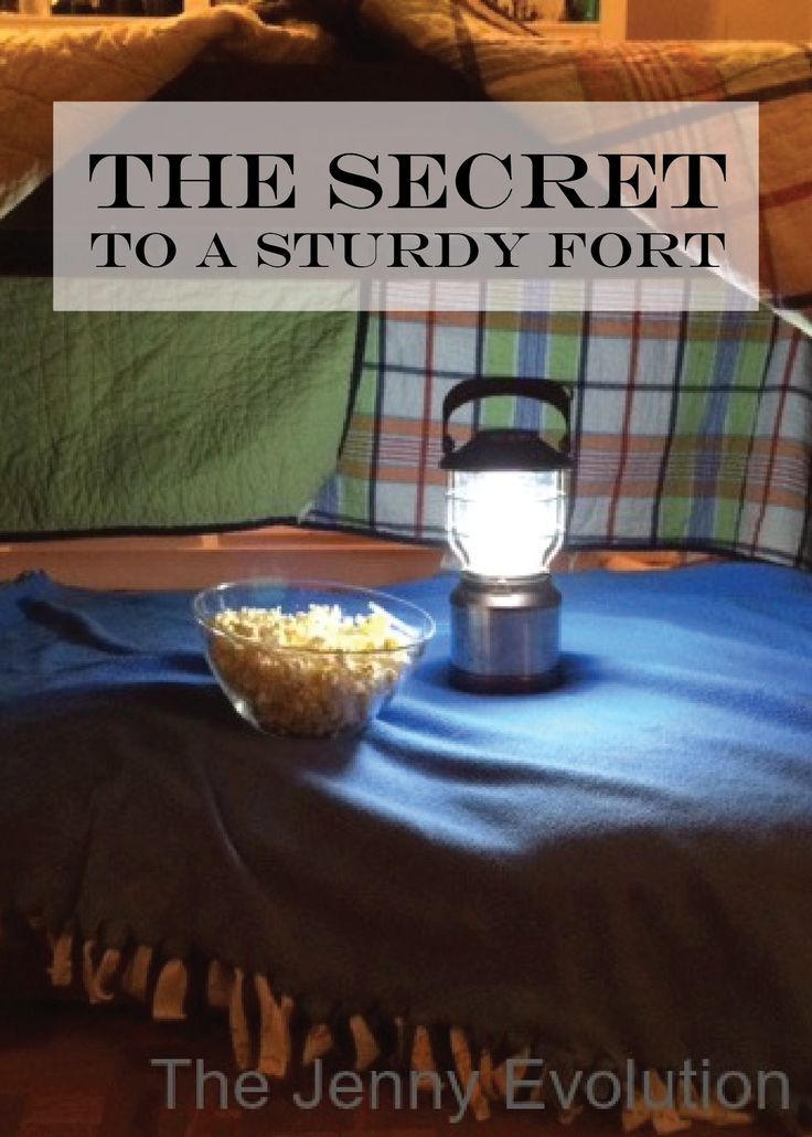 a bowl of popcorn sitting on top of a bed next to a lamp and blanket