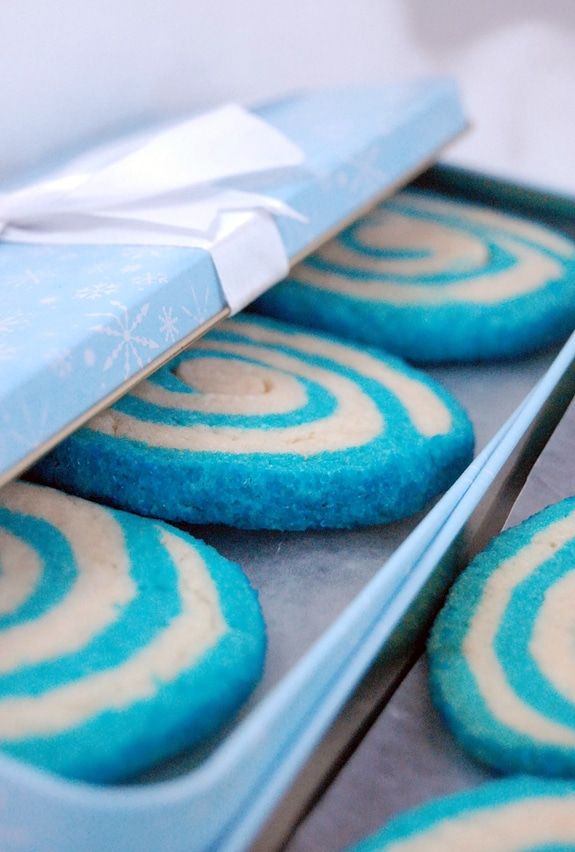 blue and white cookies in a box with a bow on it's edge, ready to be eaten