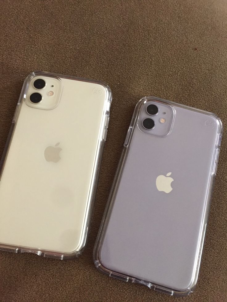 two iphones sitting next to each other on a carpeted floor in front of an apple logo