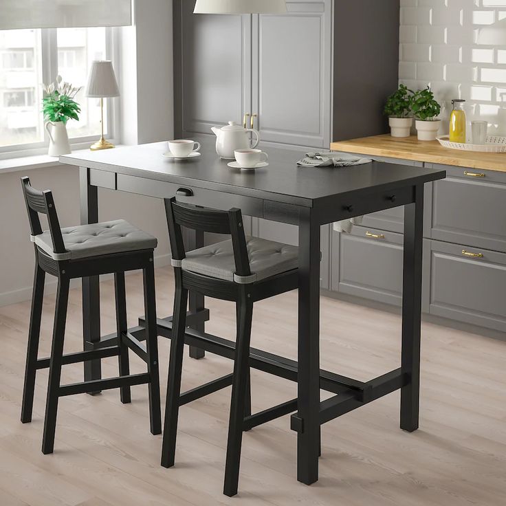 a kitchen table with two stools in front of it and an island behind it