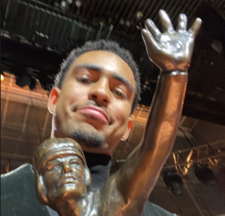 a man is holding his arm up in the air and posing for a photo next to a bronze statue