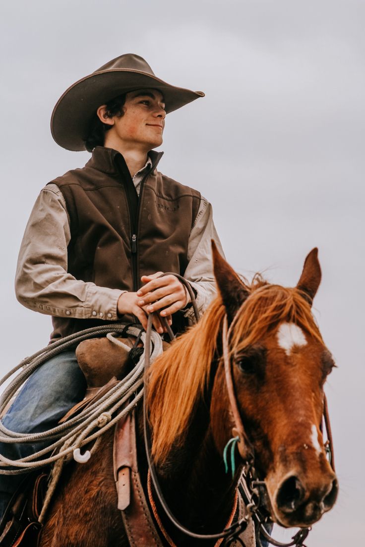 a man riding on the back of a brown horse wearing a cowboy hat and leather jacket