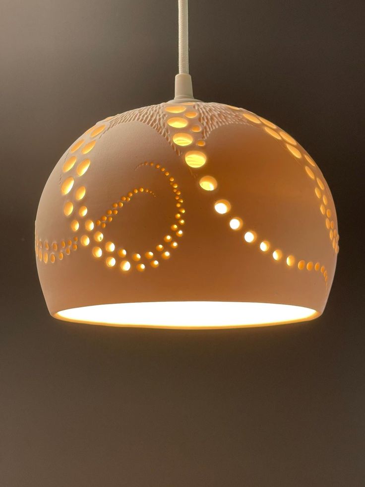 a white light hanging from a ceiling with circles and dots on the bottom of it