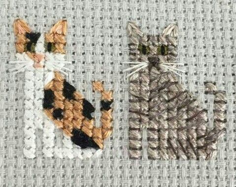 two cats made out of yarn sitting next to each other