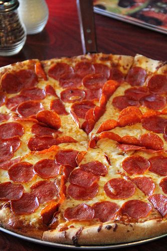 a pepperoni pizza sitting on top of a metal pan