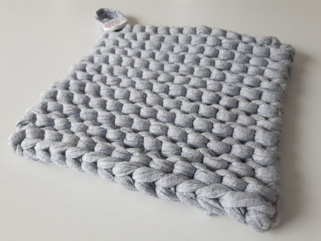 a gray crocheted blanket sitting on top of a white table