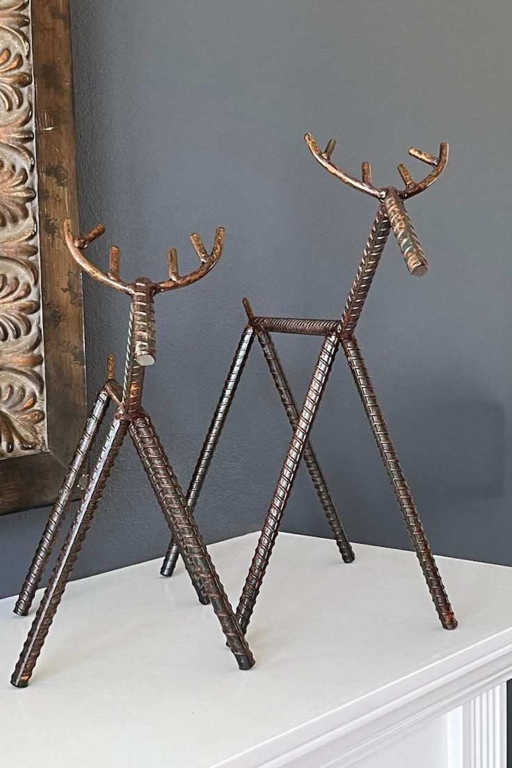 two metal deer sculptures sitting on top of a white mantle