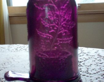 a purple glass jar sitting on top of a table next to a white doily