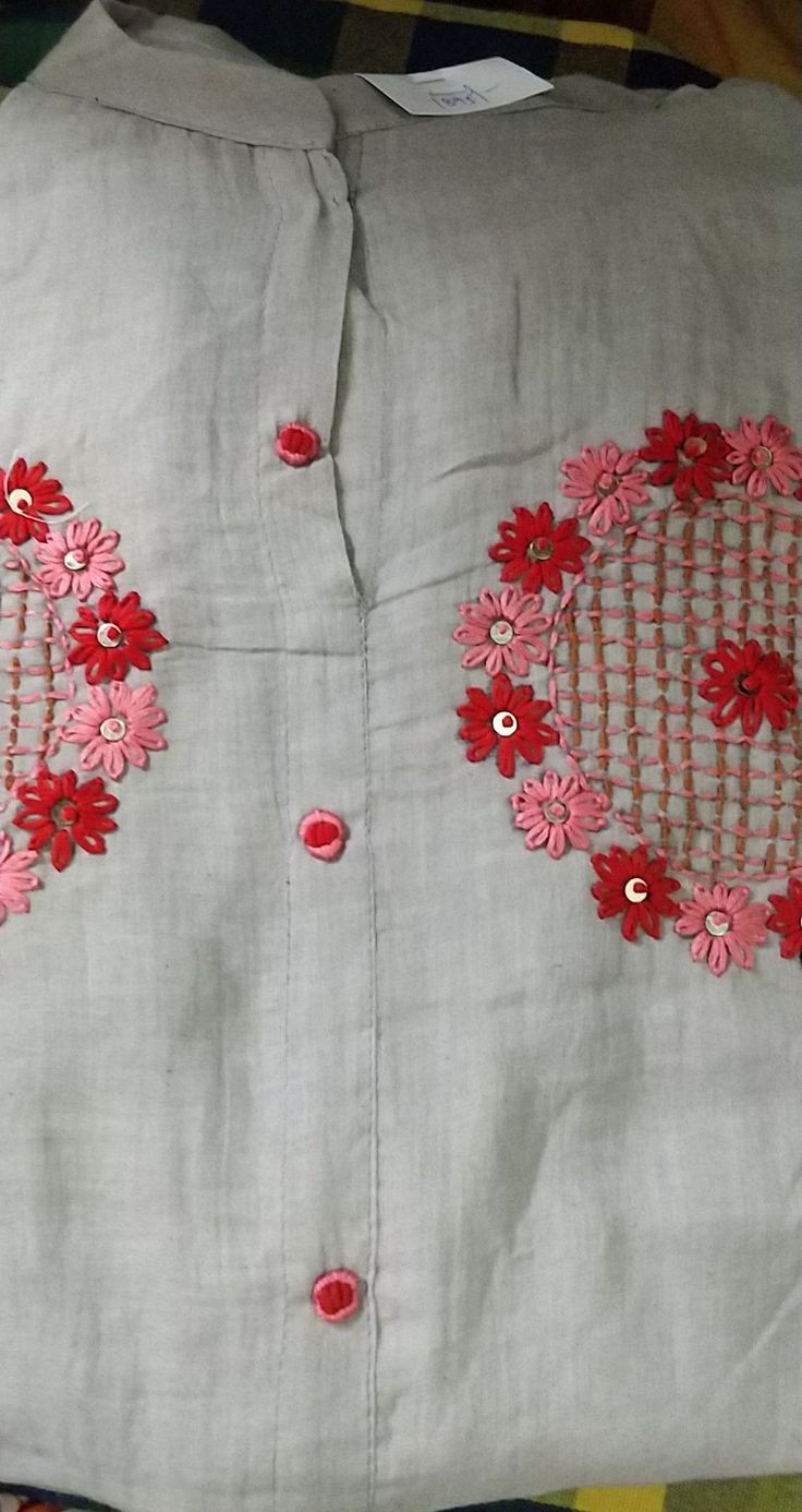 a white shirt with red flowers on the front and back, sitting on a bed