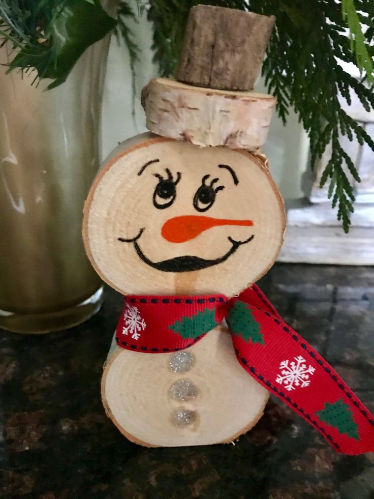 a wooden snowman ornament sitting on top of a table next to a potted plant