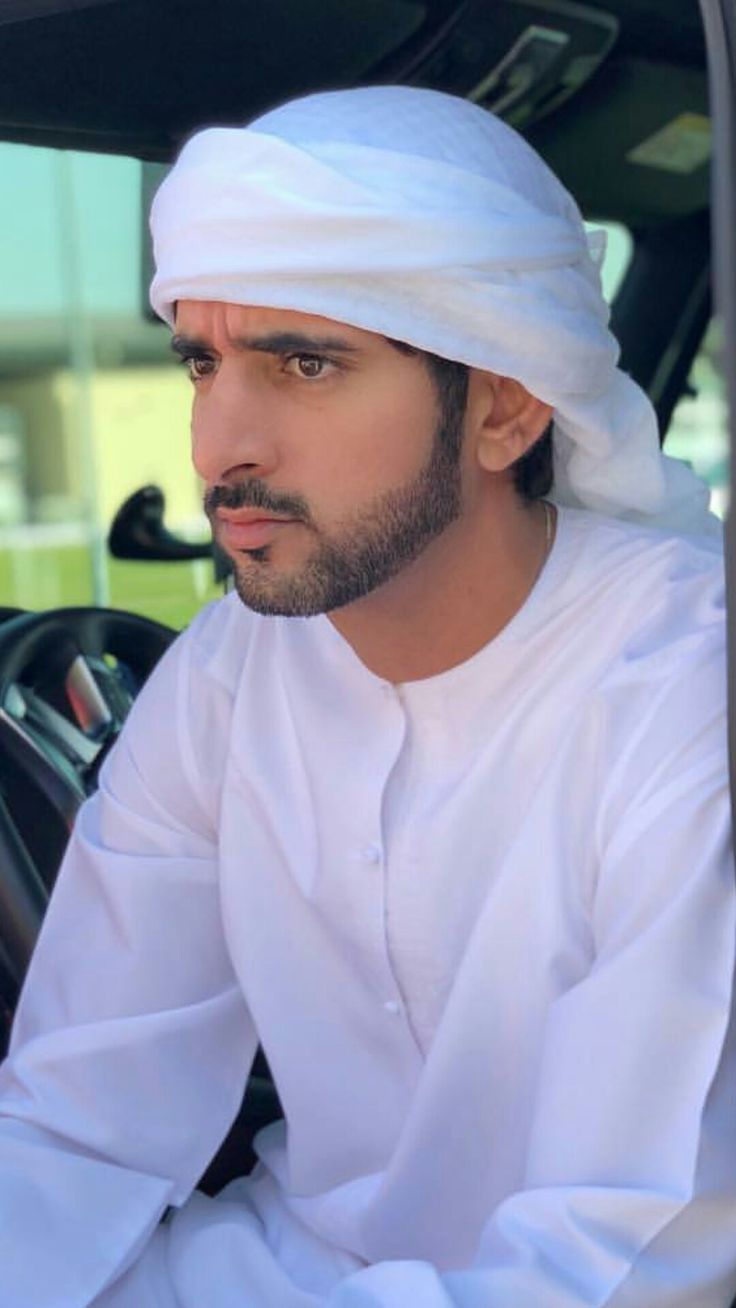 a man sitting in the driver's seat of a car wearing a white turban