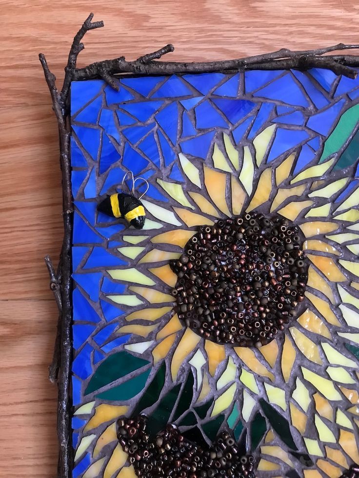 a sunflower is shown on a blue and yellow mosaic tile with a bee sitting on it