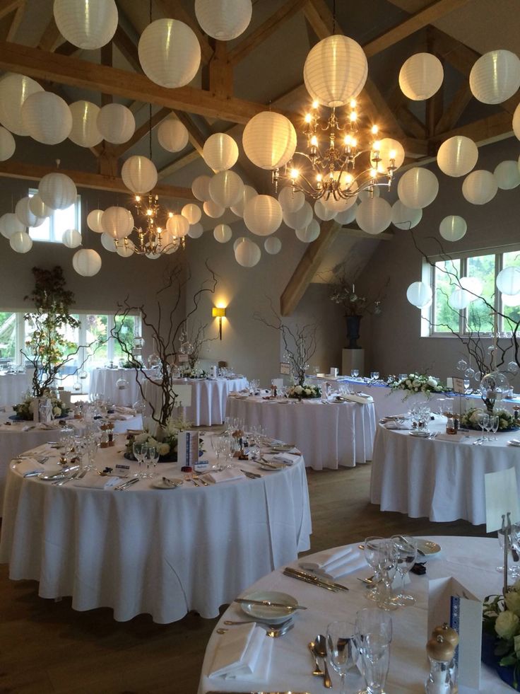 a room filled with lots of tables covered in white tablecloths and centerpieces