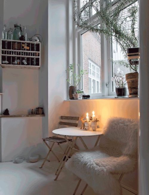 a small room with a table and chairs next to a window filled with potted plants