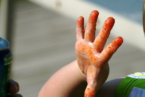 a young boy holding up his hand covered in orange paint with the letter y painted on it