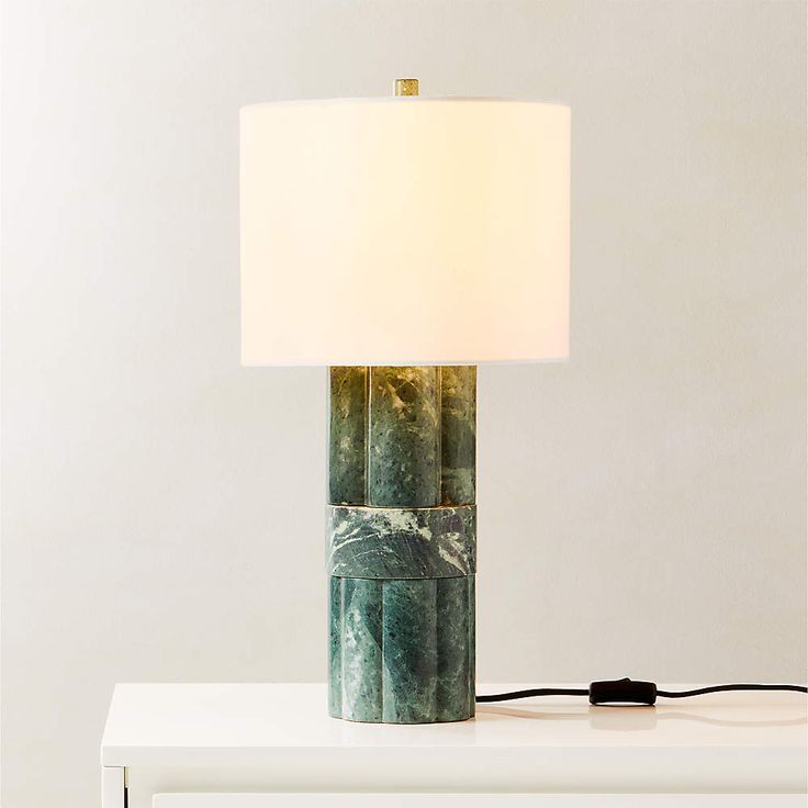 a lamp that is sitting on top of a white table next to a light fixture