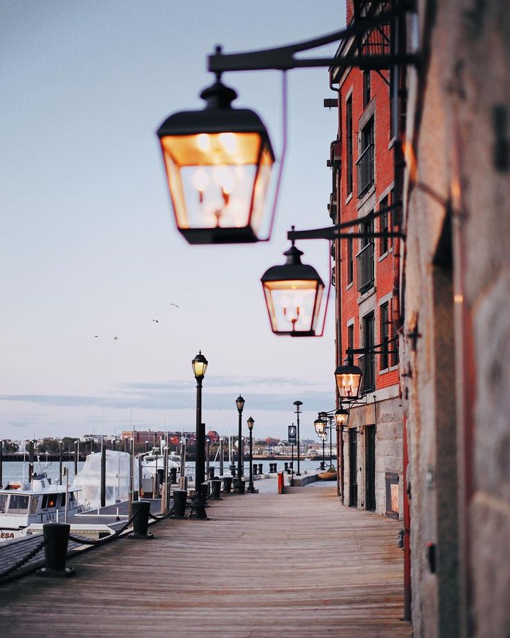 a street light hanging from the side of a building next to a dock with boats in the water