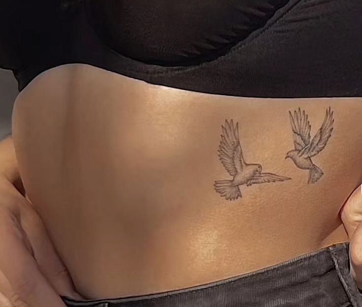 a woman's stomach with two birds on it and one bird flying in the air